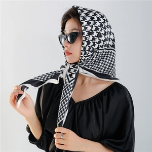 Classic black and white houndstooth silk scarf worn as an elegant headscarf by a model