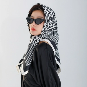 Detail of silk scarf with houndstooth pattern tied as a headband on female model