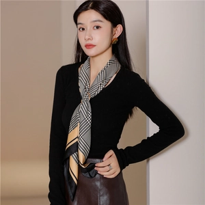 Detail of yellow and black houndstooth silk scarf tied elegantly around a model's neck