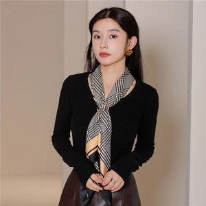 Detail of silk scarf with houndstooth pattern and golden buckle on model's outfit