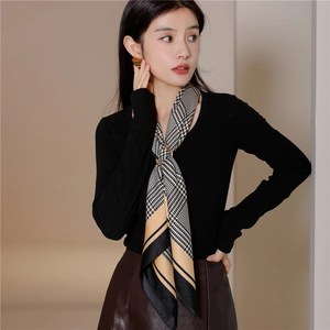 Detail of silk scarf with houndstooth pattern secured by a golden metal ring buckle