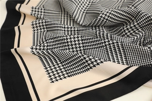 Detail shot of the black and white houndstooth pattern on a silk scarf with border