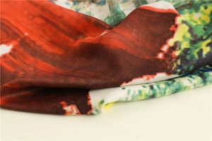 Close-up of landscape print silk scarf showing vibrant red and green artistic patterns
