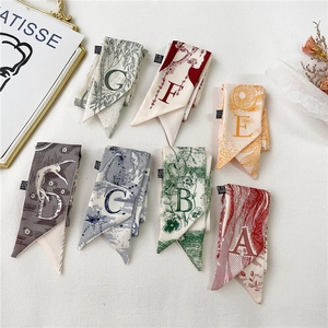 Vue à plat de sept foulards en soie double face avec lettres majuscules et motifs floraux
