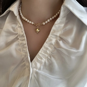 Close-up of freshwater pearl necklace featuring a golden heart pendant and OT clasp
