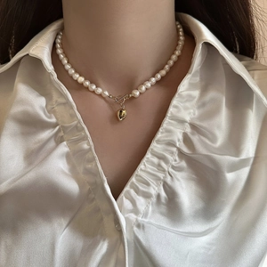 Elegant freshwater pearl necklace with golden heart pendant and OT buckle on a model