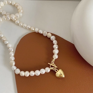 Macro detail of freshwater pearl necklace with gold heart pendant and OT toggle clasp