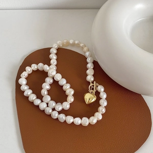 Close-up of a freshwater pearl necklace with a gold heart pendant and toggle clasp