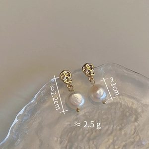 Detail view of gold textured earrings with freshwater pearls on glass tray