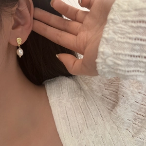 Irregular textured gold-plated pearl drop earrings worn with elegant lace attire