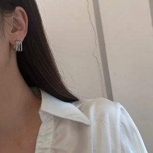 Close-up of triple-layered silver geometric earrings worn by a model in a minimalist style