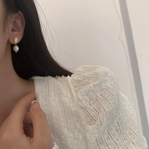 Irregular textured gold earring with freshwater pearl detail on a female model