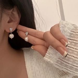 Detailed view of baroque pearl drop earrings with irregular silver metal design on ear