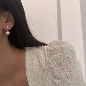 Irregular textured silver earrings with freshwater pearl pendant shown on a model
