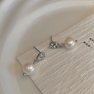 Detailed view of silver textured earrings with white freshwater pearls on a display card
