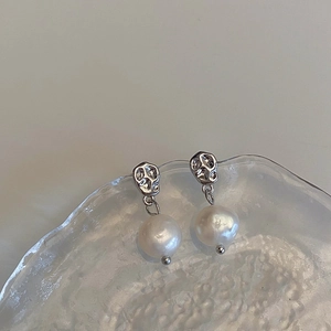 Macro detail of irregular silver metal stud earrings with elegant white pearl pendants