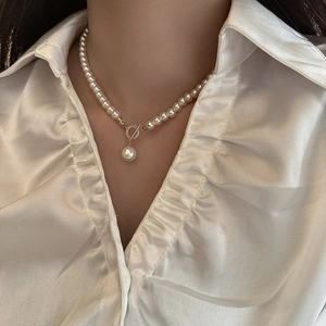 Gros plan d'un collier en perles d'eau douce avec fermoir à bascule doré et pendentif perle