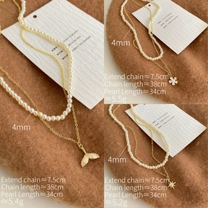 Detailed close-up of double-layer pearl necklace with fishtail, flower, and star pendants