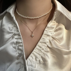 Double-layered pearl choker necklace with a gold star pendant on a white silk background