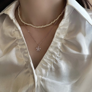 Double-layered pearl necklace featuring a floral pendant with sparkling crystals on a model