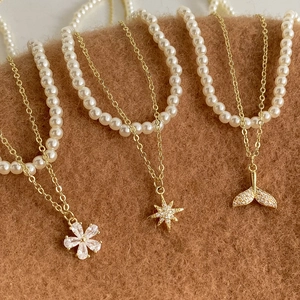 Double-layered gold pearl necklace with floral, star, and fishtail zircon pendants