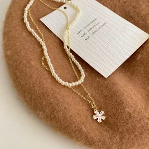 Close-up of double-layer necklace with white pearls and gold flower zircon pendant