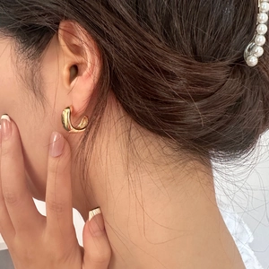 Detailed view of glossy gold geometric C-shaped earrings on a model for daily wear