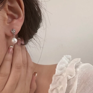Vue détaillée d'une boucle d'oreille texturée argentée avec une perle blanche ronde