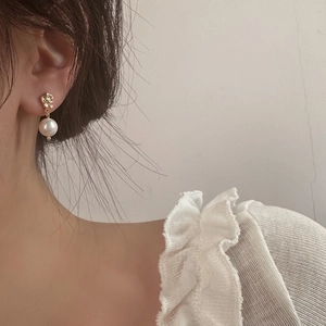 Gros plan de boucles d'oreilles dorées irrégulières avec perle sur un mannequin