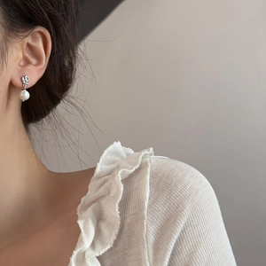 Boucles d'oreilles argentées à texture plissée et perles blanches portées par un mannequin