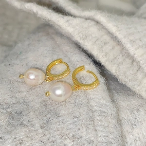 Detail of gold-plated hoop earrings with micro-set zircon and white freshwater pearl pendant