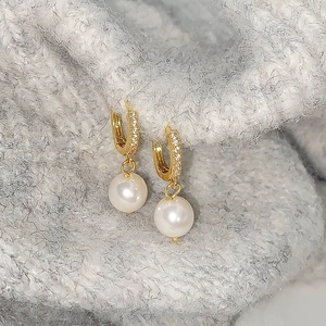 Detail of freshwater pearl earring with gold-plated zircon pavé hoop on grey knitwear