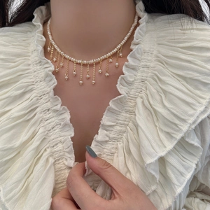 Dettaglio delle perle barocche sulla collana con nappe placcata in oro indossata da una modella