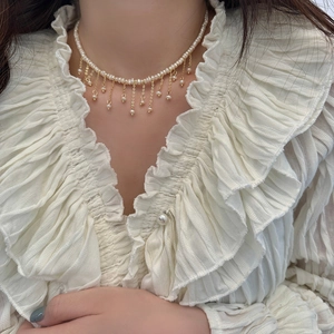 Dettaglio della collana di perle d'acqua dolce barocche con nappine dorate sul collo