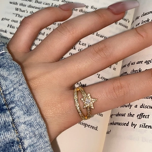 Close-up of double-layered gold ring with a sparkling pavé zircon star on a model's hand