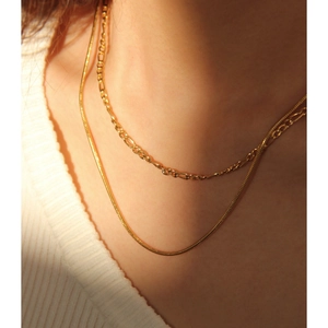 Close-up of double-layer gold snake and figaro chain necklace set on model's neck