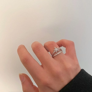 Detail of a sparkling double-layered silver star ring with zircon stones on finger