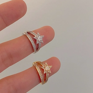 Detail of star-shaped zircon rings in gold and silver finish worn on a finger