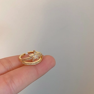 Detail of double-layered gold open ring featuring a sparkling zircon star on the finger