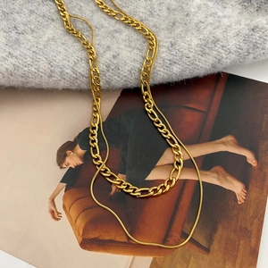 Macro detail of gold-plated double-layered Figaro and snake chain necklace set