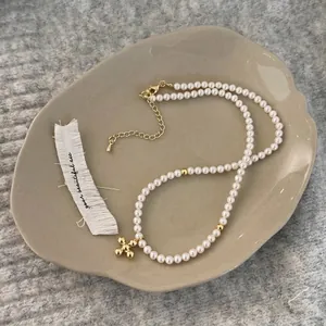 Elegant pearl necklace with gold cross pendant on a chic ceramic display tray