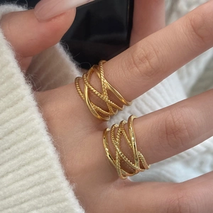 Multi-layer gold-plated cross ring with smooth and twisted bands on model's hand