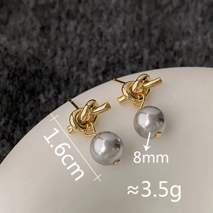 Macro view of gold knot stud earrings featuring detailed size and weight specifications