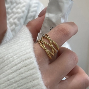 Detail of layered gold-plated crossover ring with smooth and twisted rope textures