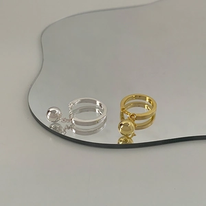 Detailed view of adjustable chain rings with gold and silver ball pendants on a mirror