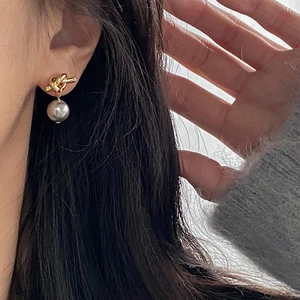 Close-up of vintage knot earrings with elegant gray pearls on model's ear