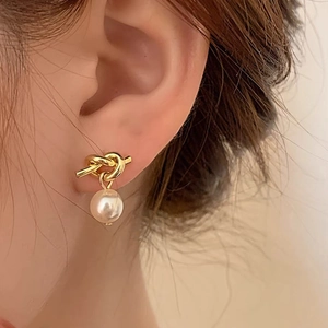 Detailed close-up of a French knot pearl earring featuring a lustrous white bead