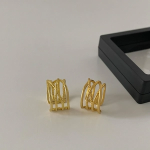 Detail of minimalist multi-layered gold plated ear cuffs with twisted rope texture design