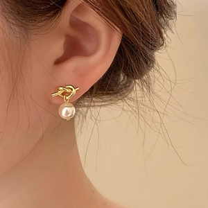 Detail of French vintage knot pearl earring featuring a gold metallic twist and white pearl