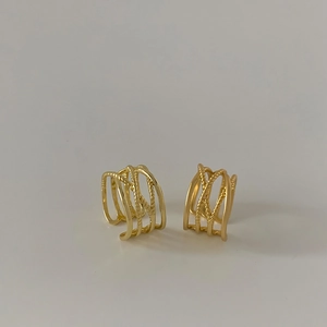 Detail of gold layered ear cuffs featuring smooth and twisted rope textures in retro style
